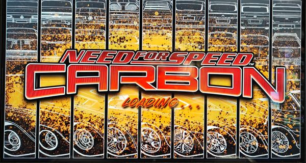 The pre-race loading screen for Need For Speed Carbon arcade. It has the game logo in red text in the foreground, and outlines showing off different cars against a yellow splash graphic. 