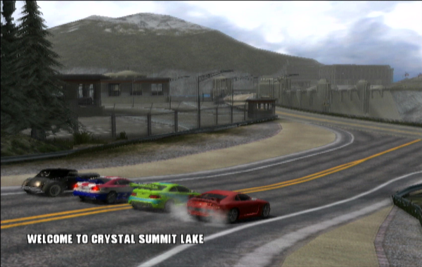 Four cars lined up side by side at the start of a race in Burnout 2: Point of Impact. They are about to drive across a dam at the Crystal Summit Lake track.