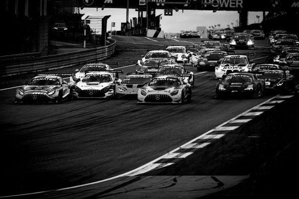 The start of a GT World Challenge race at the Nurburgring, with a swarm of GT3 cars under braking for the first turn. The photo has been edited to be black and white.