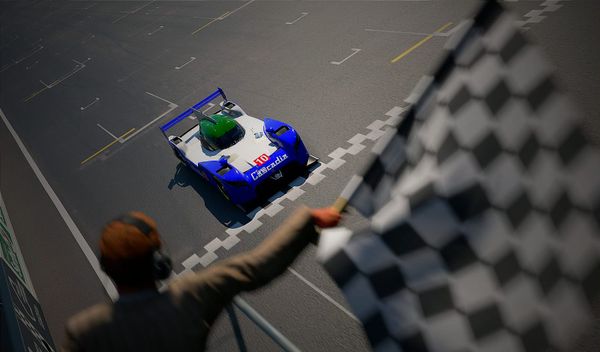 A blue, white and green Nissan GT-R LM NISMO race car crossing the finish line at a race, from the perspective of the flag man.