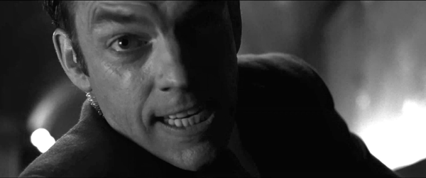 Agent Smith, played by Hugo Weaving, has a defiant grin on his face as he attempts to choke out Neo, played by Keanu Reeves, in The Matrix