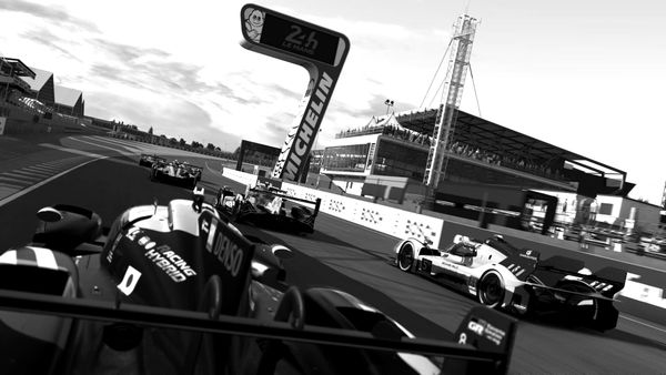 Six Le Mans Hypercars on the front straight at Circuit De La Sarthe at the start of a race.