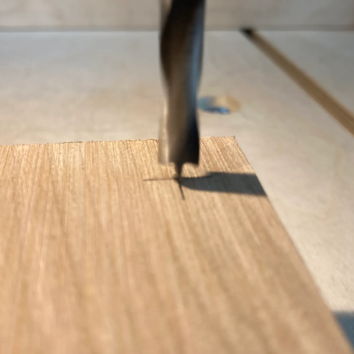 An image showing a brad point drill making contact with an indentation in a piece of wood.