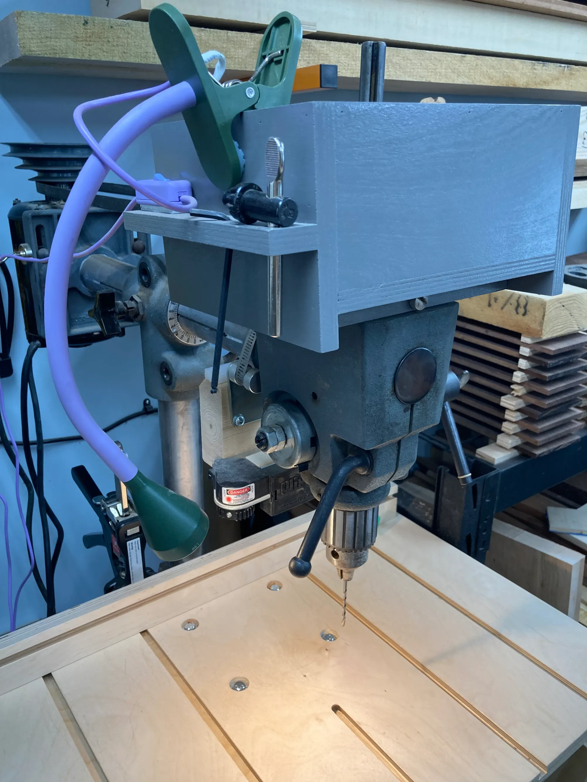 A gooseneck lamp clipped to a drill press.
