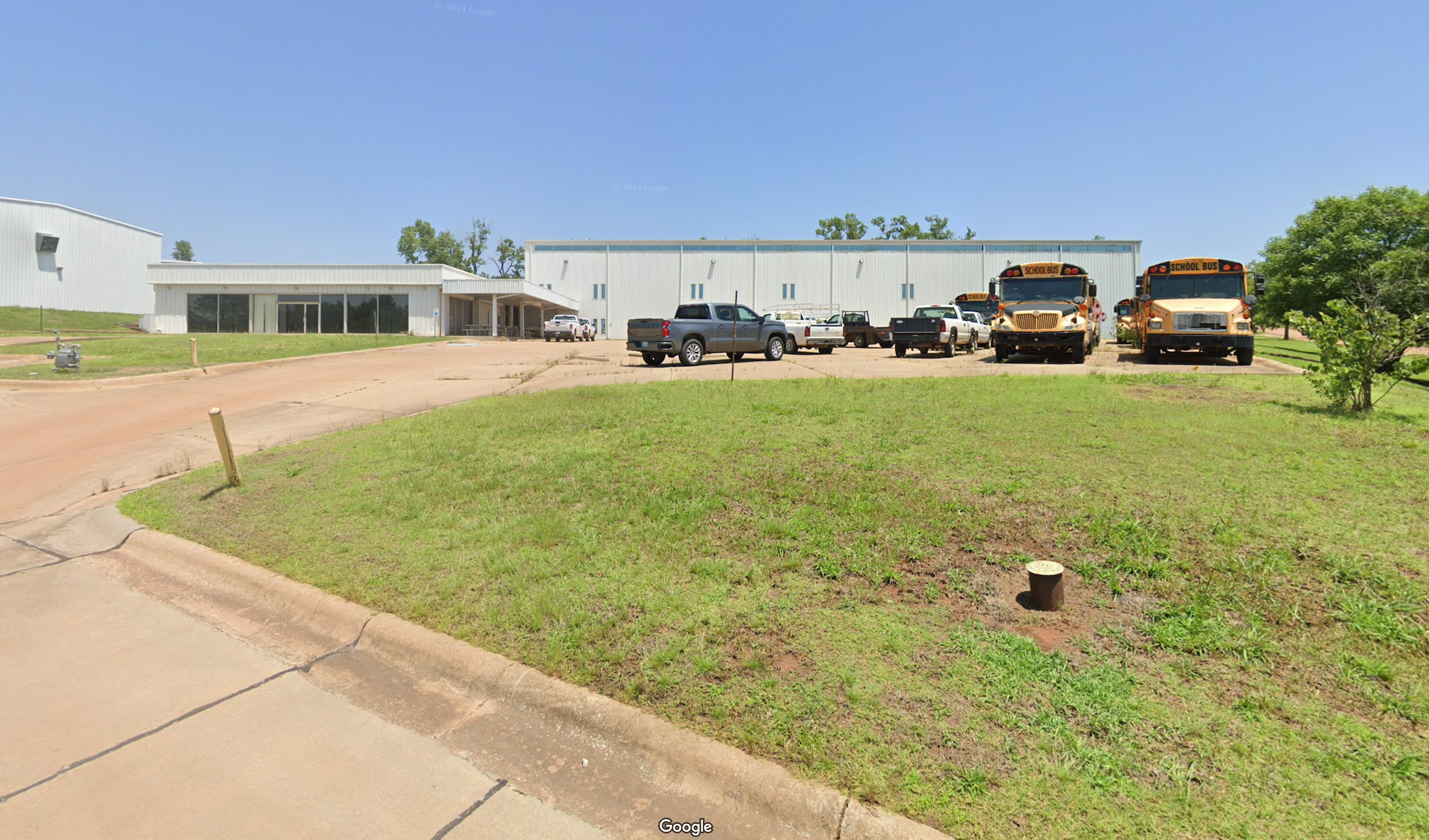 Storage warehouses, office building, parking lot with vehicles and school buses