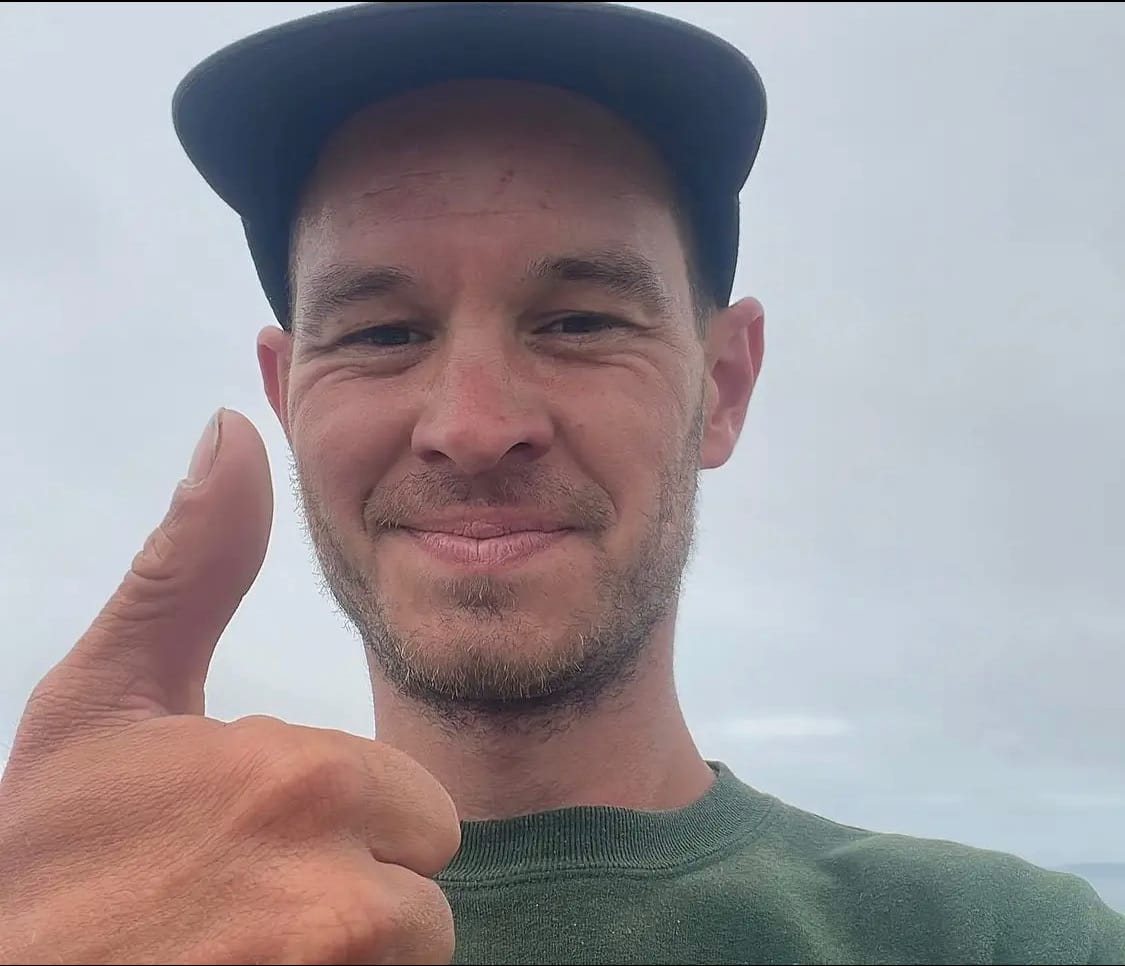 Grady Lambert wearing a cap and green shirt, smiling and giving a thumbs up gesture during his 2022 cross-country run to thank healthcare workers
