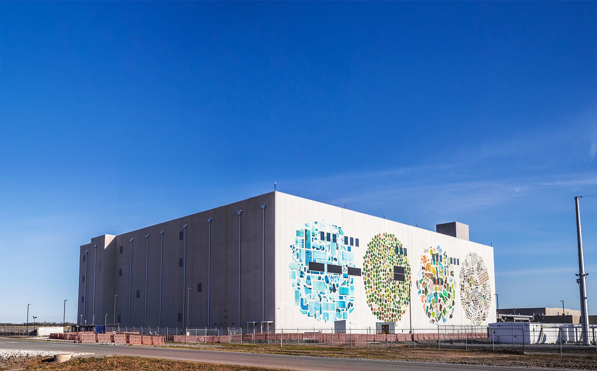 Google data center building in Mayes County, Oklahoma with three large circular murals painted on its white exterior wall.