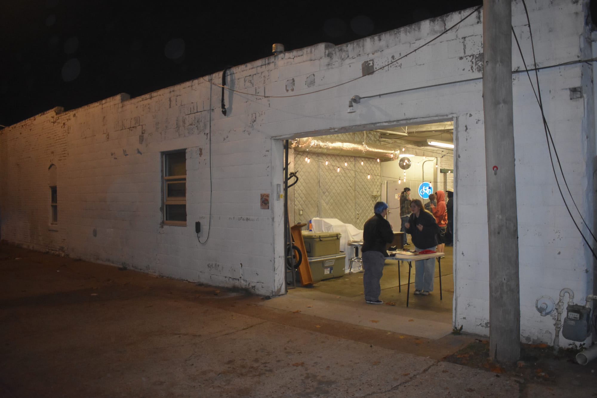 Garage door entrance to The Bait Shop music venue in Stillwater, showing illuminated interior space with people at the entrance.
