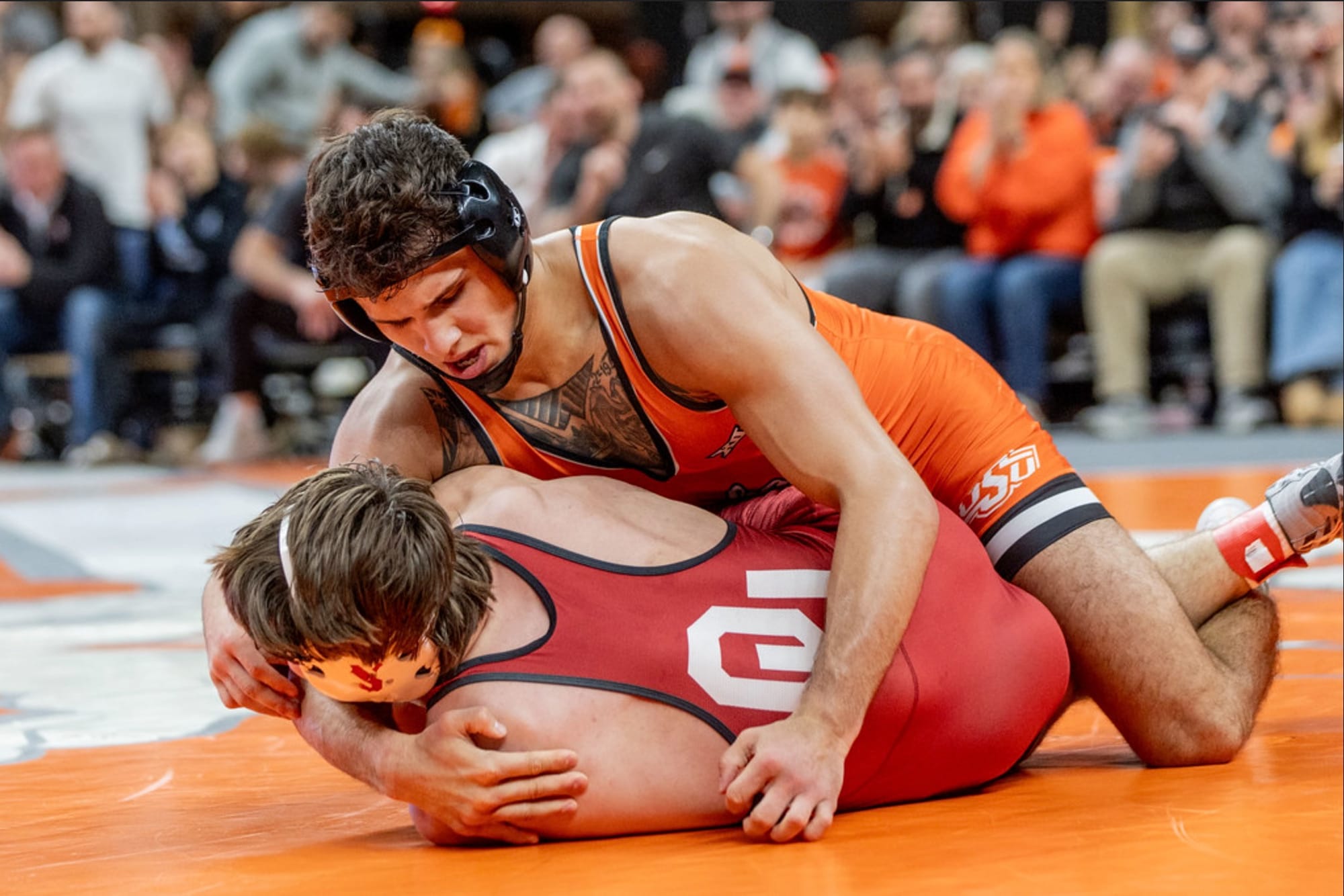 Oklahoma State wrestler Alex Facundo in orange singlet controls Oklahoma opponent in red singlet on mat during 174-pound match on Jan. 11, 2026, at Gallagher-Iba Arena in Stillwater, Oklahoma.