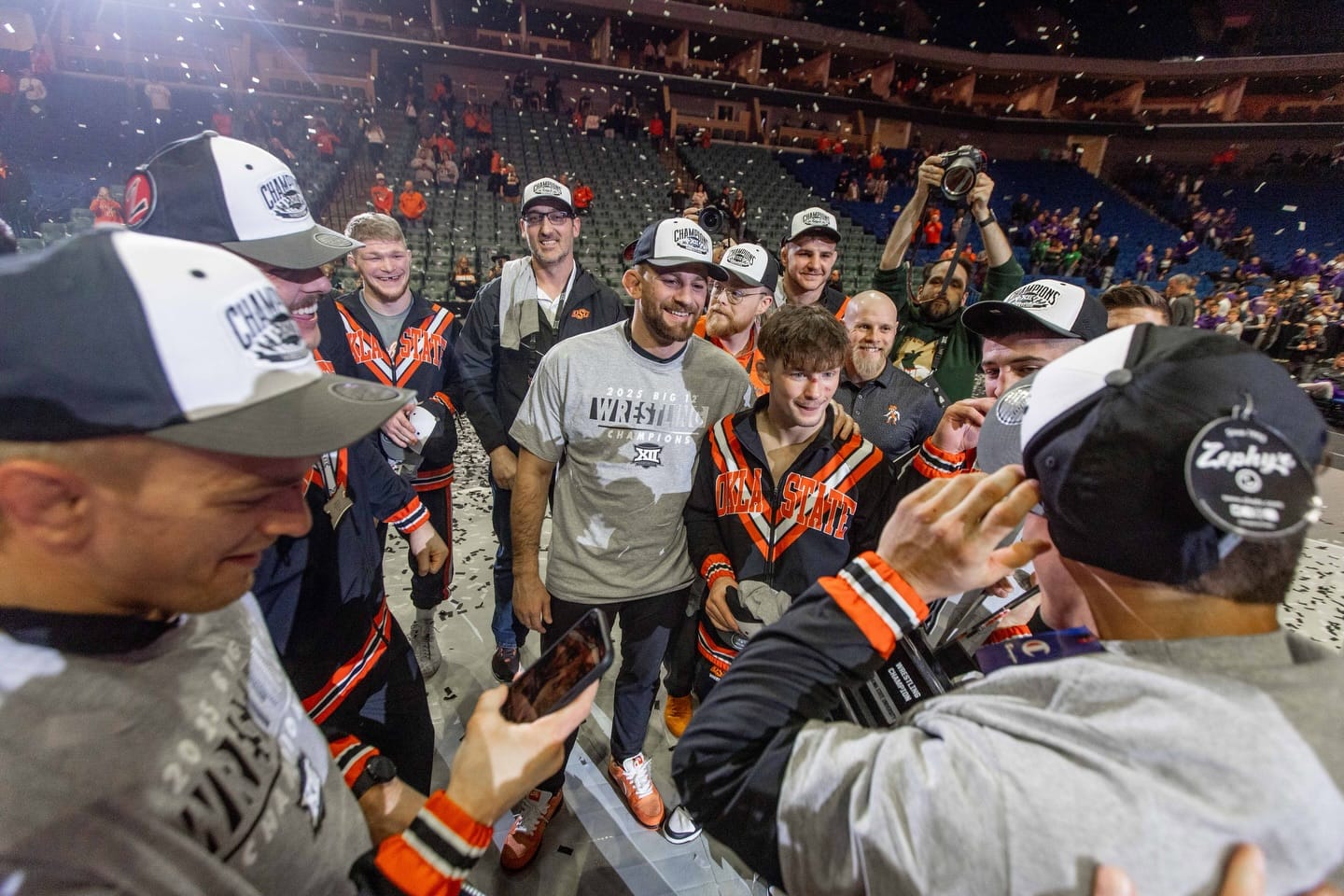 OSU head coach David Taylor and wrestler Troy Spratley celebrate surrounded by Cowboys and confetti after winning the 2025 Big 12 Wrestling Championship.