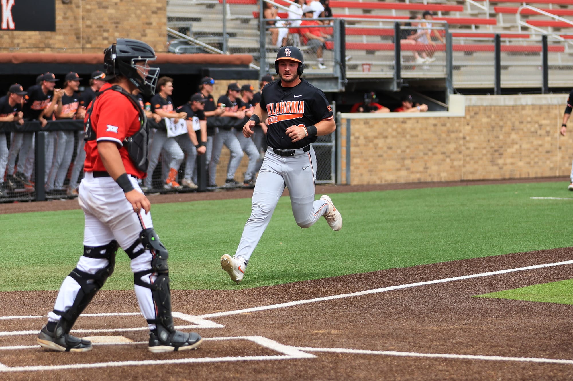 Oklahoma State center fielder Kollin Ritchie scores at Rip Griffin Park as the Cowboys' dugout celebrates during OSU's 9-8 win over Texas Tech in Lubbock, Texas.