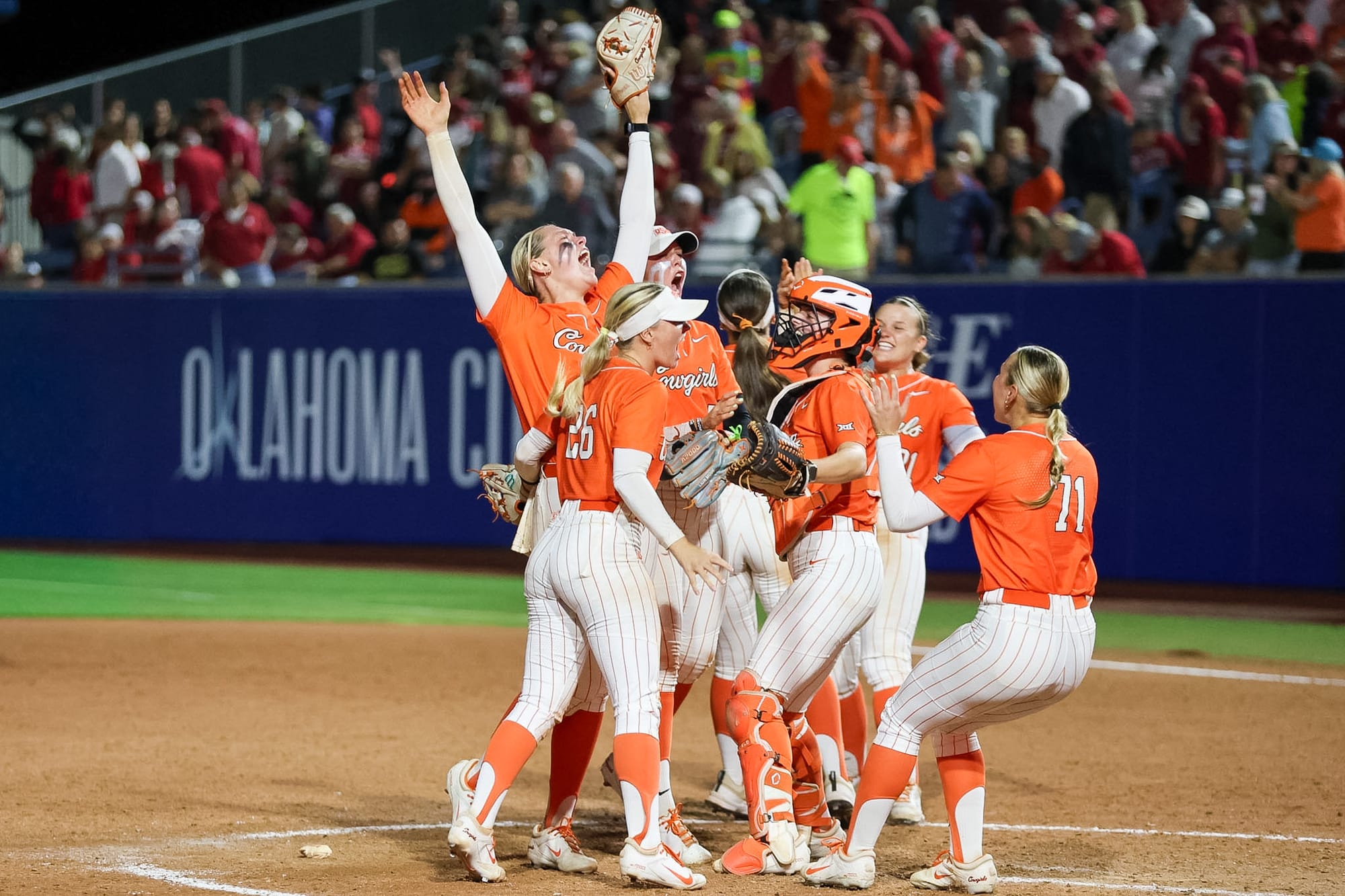 Oklahoma State softball players celebrate on the pitcher's mound after defeating top-ranked Oklahoma 6-4 at Devon Park in Oklahoma City.