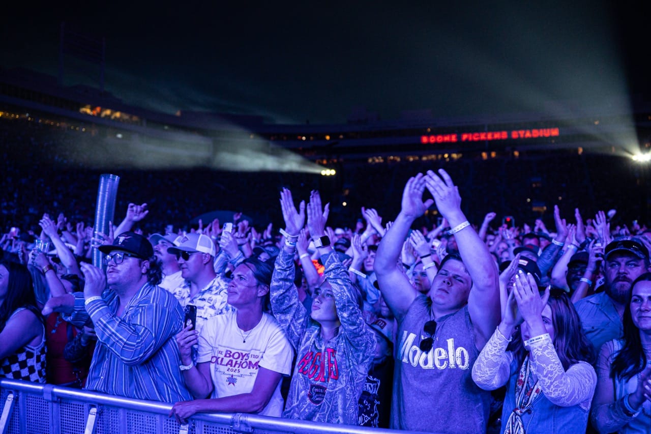 Thousands of fans raise their hands inside a packed Boone Pickens Stadium in Stillwater at night during the Boys from Oklahoma concert on April 11, 2026.