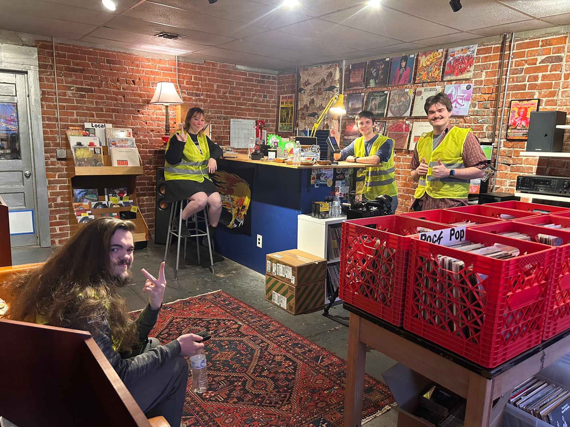 Four OSU Filmmakers Association members in yellow safety vests pose inside Velvet Fudge in Stillwater ahead of the March 27 Release Radar OSU showcase.