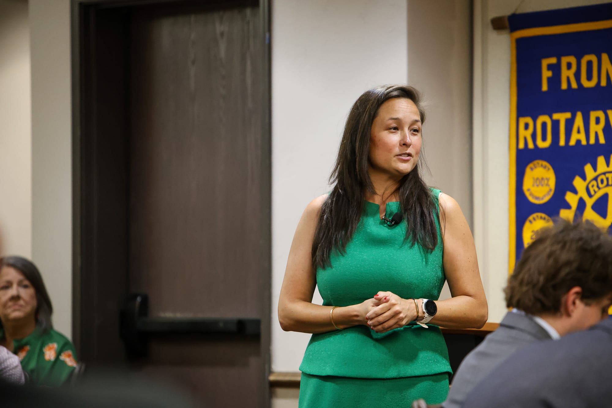 Cyndi Munson, wearing a green dress, gestures while speaking to the Stillwater Frontier Rotary Club on July 23, 2026.