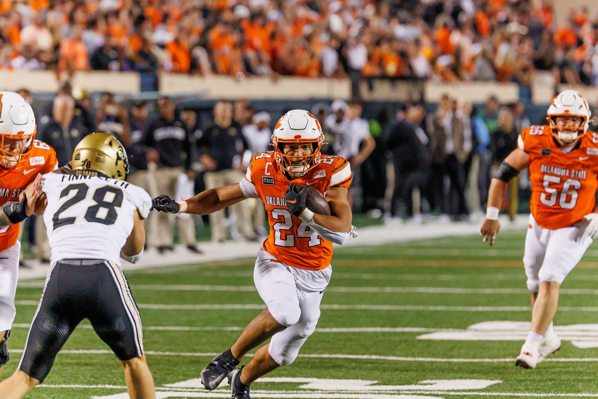 OSU running back Caleb Hawkins carries the ball toward Colorado defender Ben Finneseth as lineman Tyler Mercer trails on Oct. 24, 2026, at Boone Pickens Stadium.