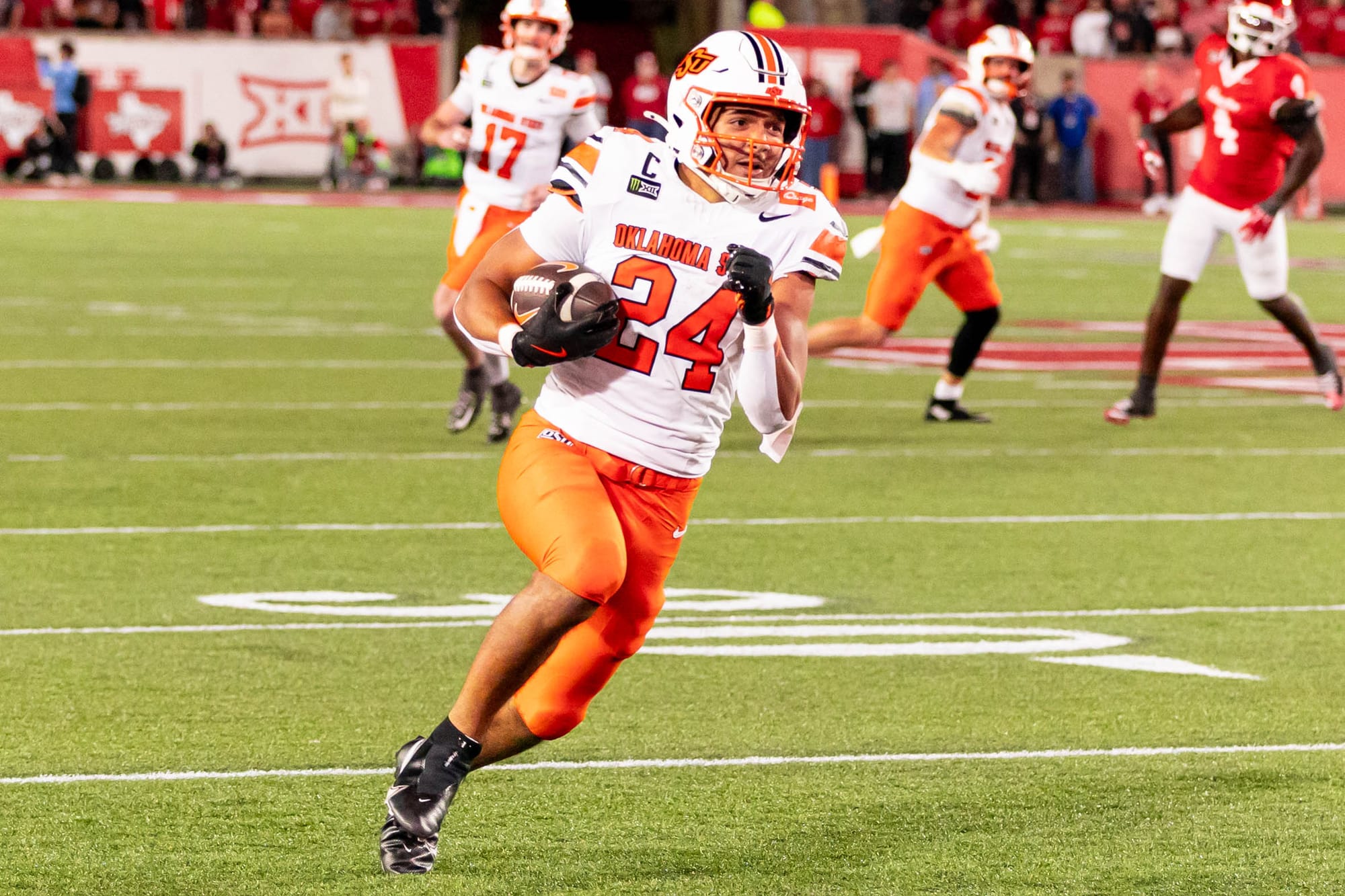 OSU running back Caleb Hawkins (24) carries the ball upfield after hurdling a defender against Houston on Oct. 17, 2026, at TDECU Stadium in Houston.