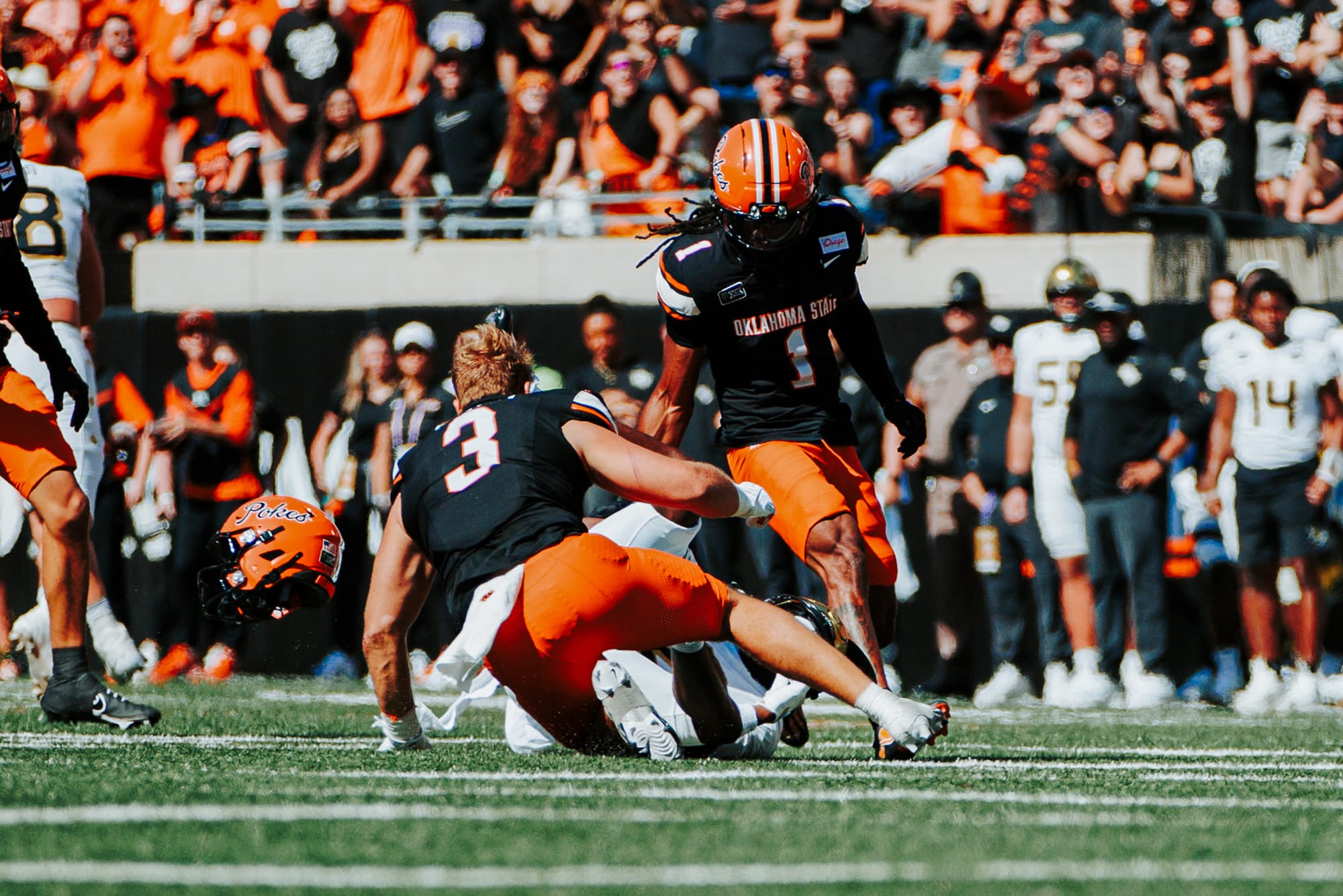 OSU linebacker Tate Romney, his helmet flying off, tackles UCF’s Tyren Hornes for a 10-yard loss as safety Evan Jackson closes in on Oct. 10, 2026, at Boone Pickens Stadium.