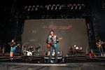 Wyatt Flores sings and plays guitar at center stage at Boone Pickens Stadium in Stillwater on April 11, 2026, flanked by bandmates and a vintage pickup truck.