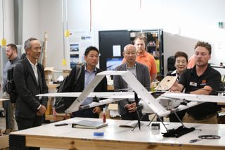 Allan Burba demonstrates a white long-range drone to Japanese delegation members at OAIRE laboratory in Stillwater