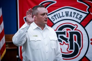 Duane Helmberger raises his right hand while taking oath of office as Stillwater Fire Chief