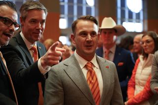 Eric Morris in gray suit and orange striped tie speaks with OSU athletic director Chad Weiberg at Morris' introductory press conference Dec. 8, 2025, at the OSU Alumni Center in Stillwater
