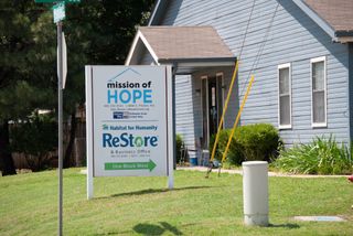 Mission of Hope sign stands in front of light blue building in Stillwater. The organization also houses Habitat for Humanity ReStore at the South Perkins Road location.