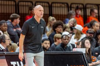 Oklahoma State head coach Steve Lutz stands on the sideline during a game at Gallagher-Iba Arena, wearing a black Cowboys polo shirt and khaki pants while coaching his team