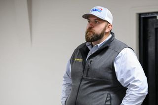 Dillon Travis wearing a white campaign cap and gray vest speaks at a November 2025 campaign event in Pawnee, Oklahoma