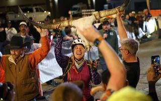 Kristen Owenreay raises the DFL longhorn skull trophy overhead at the Mid South finish line in Stillwater, Oklahoma, on March 14, 2026, flanked by Brad Connelly and Bobby Wintle.