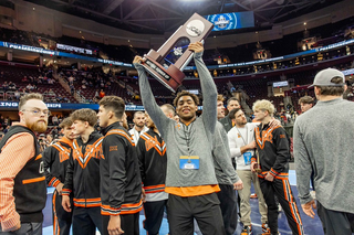 Dee Lockett raises the NCAA runner-up trophy on the arena floor at Rocket Mortgage Fieldhouse, surrounded by OSU teammates, March 21, 2026.