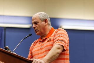 Steve Trost speaks at a podium during Stillwater City Council public comment on the short-term rental ordinance, May 18, 2026, wearing an Oklahoma State University polo shirt.