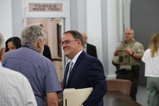 District Attorney Jeremiah Gregory, holding a stack of files, smiles while talking with a man outside the district courtroom after his swearing-in July 31, 2026, at the Payne County Courthous