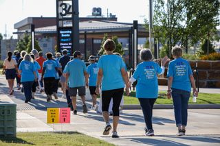 Participants in P.E.O.'s Walk Today for Women Tomorrow walk past route markers at Block 34 in Stillwater on Saturday, Aug. 1, 2026, with the Block 34 sign visible in the background.