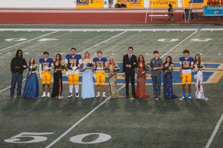 Stillwater High’s 2026 homecoming court and escorts stand near midfield at Pioneer Stadium, with crowned king Kyle Stokes (23) and queen Daisy Goff at center, before Friday’s game.