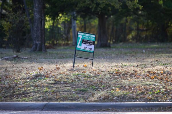 Public hearing sign on vacant lot at 802 S. Western Road showing rezoning request from RSS to O with hearing dates of Nov. 4, 2025 and Nov. 17, 2025