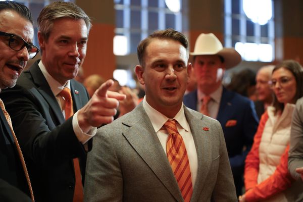 Eric Morris in gray suit and orange striped tie speaks with OSU athletic director Chad Weiberg at Morris' introductory press conference Dec. 8, 2025, at the OSU Alumni Center in Stillwater