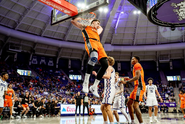 Oklahoma State center Andrija Vukovic (19) in orange uniform hangs from the rim after completing a dunk at Schollmaier Arena during the Cowboys' 68-65 loss to TCU Tuesday night in Fort Worth.