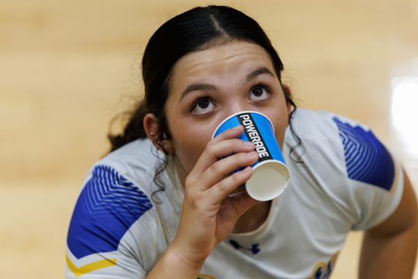 A closeup photo of a volleyball player drinking out of a powerade branded cup with eyes looking up