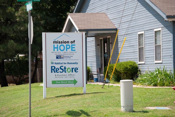 Mission of Hope sign stands in front of light blue building in Stillwater. The organization also houses Habitat for Humanity ReStore at the South Perkins Road location.