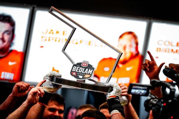 Hands hold up the Bedlam Series trophy featuring the rivalry's logo after Oklahoma State's 27-24 victory over Oklahoma in the final Bedlam football game November 2023