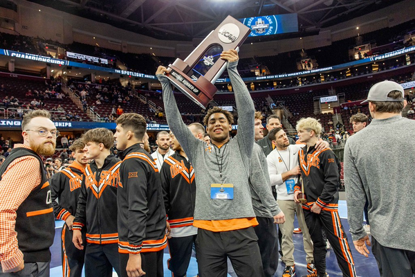 Dee Lockett raises the NCAA runner-up trophy on the arena floor at Rocket Mortgage Fieldhouse, surrounded by OSU teammates, March 21, 2026.