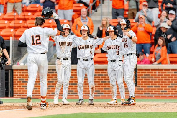 Colin Brueggemann (12) approaches home plate as Brock Thompson (1), Campbell Smithwick (4), Danny Wallace (9), and Deacon Pomeroy (45) wait after his grand slam vs. Missouri State.