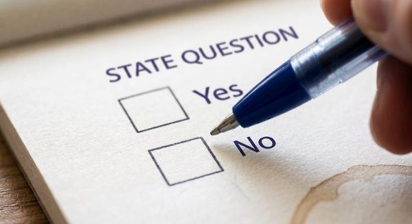 AI-generated illustration of a hand holding a blue pen over a paper ballot reading "State Question," with unmarked boxes next to "Yes" and "No."