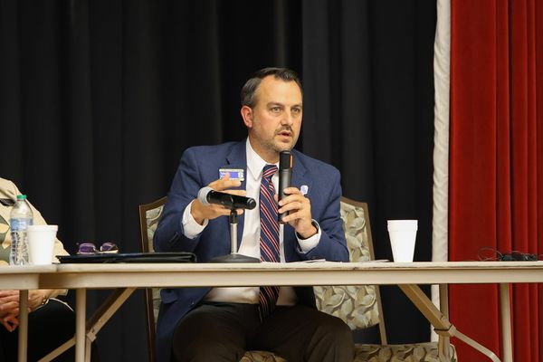 Stillwater Public Schools Superintendent Tyler Bridges speaks into a microphone during a panel discussion on classroom technology Aug. 27, 2026, at the Stillwater Public Library.