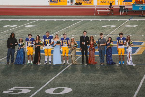 Stillwater High’s 2026 homecoming court and escorts stand near midfield at Pioneer Stadium, with crowned king Kyle Stokes (23) and queen Daisy Goff at center, before Friday’s game.