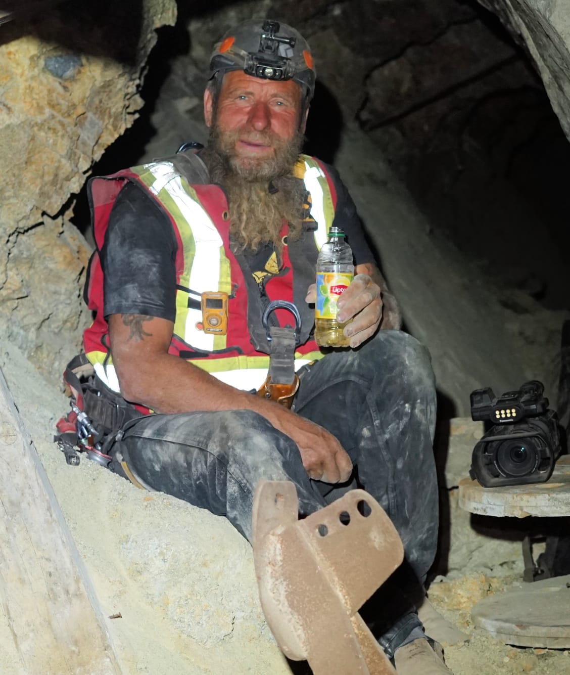 Frank Schlichting in a climbing helmet, headlamp lit, checking his gas detector underground