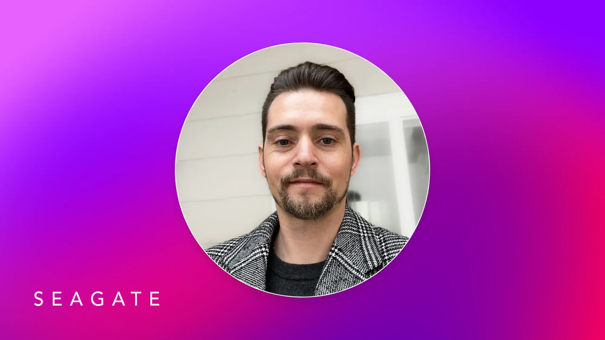 Seagate employee headshot of man with short dark hair and beard wearing a checkered coat on purple gradient background with SEAGATE text