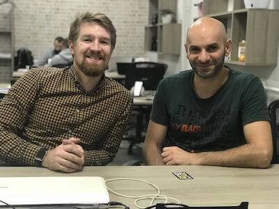 Zeroqode co-founders Vlad and Levon sitting at a table smiling.