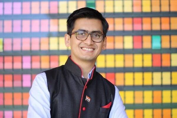 Gaurav J. wearing a white shirt and a sleeveless black vest with dark hair and glasses.